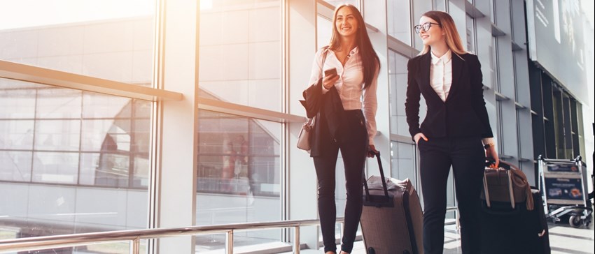 People in suits walking through the airport with luggage